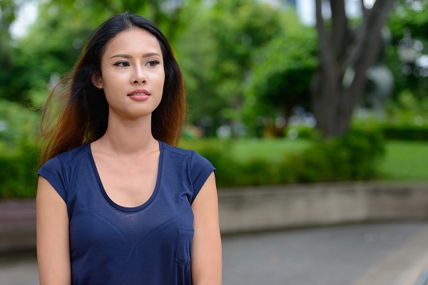 Young beautiful Thai woman sitting in a park posing for a photo all alone