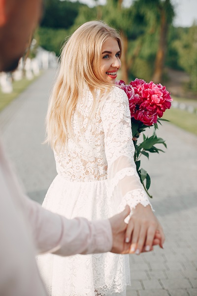 Beautiful smiling German girl spending time with her boyfriend walking in a garden