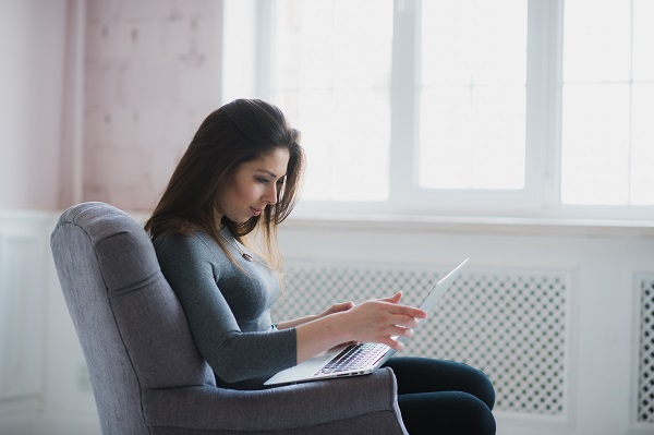 Pretty Icelandic lady working on her laptop while sitting in an armchair