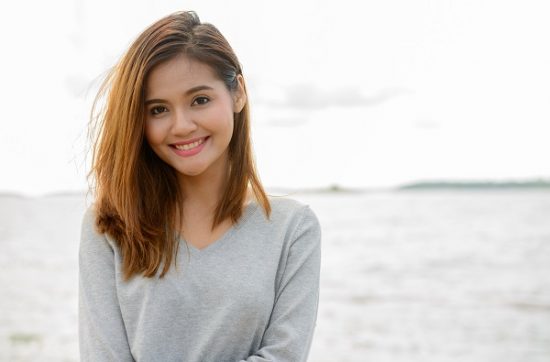 Young beautiful Thai woman against a scenic view of the lake