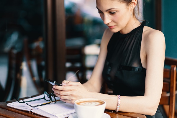 Beautiful Icelandic business lady drinking a cup of coffee and uses her phone