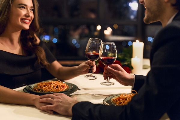 Smiling charming Spanish woman drinking a glass of red wine with her boyfriend