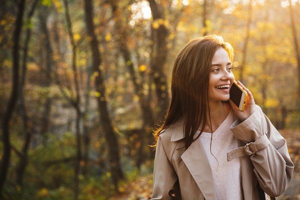 Image of a young Ukrainian woman using her smartphone while walking in an autumn park