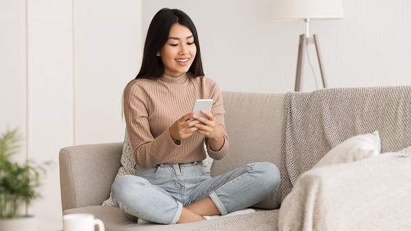 Smiling Cambodian lady sitting on a sofa with a phone