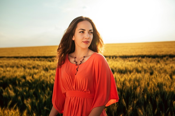 Attractive smiling Greek woman standing in a wheat field all by herself