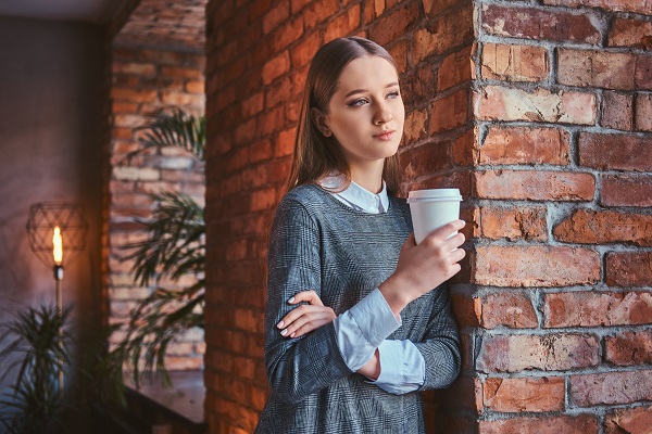 Serious Slovakian lady standing with a cup of coffee looking away