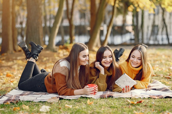 Three young attractive Lithuanian girls lying on a blanket during an autumn day