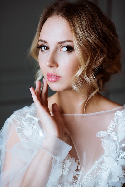 Charming young Danish woman touching her face with a finger wearing a white robe