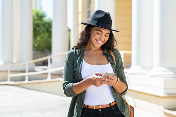 Smiling Panamanian lady standing with her phone on the street