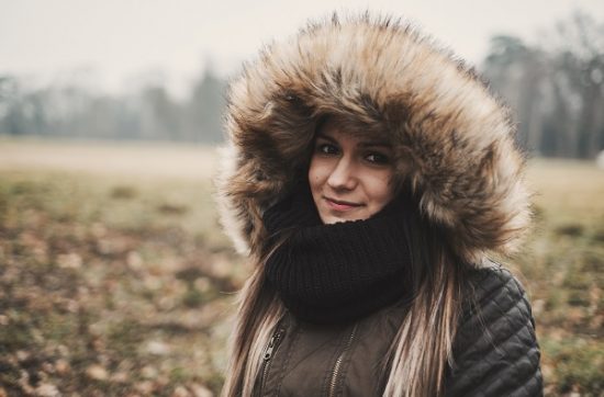 Winter portrait of a young smiling Serbian woman posing for the camera in a field