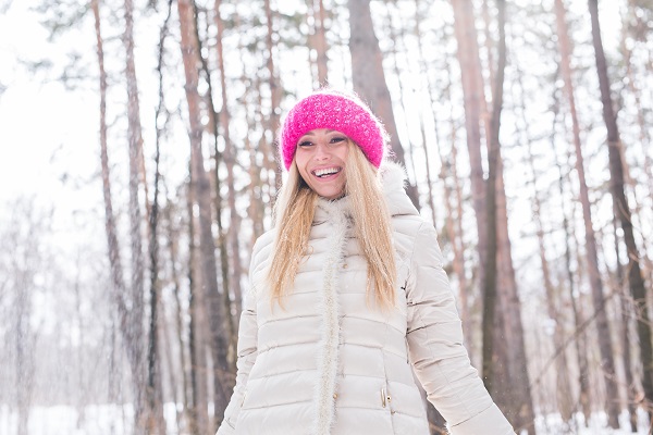 Young pretty Swedish woman throwing snow in the air during her winter holidays