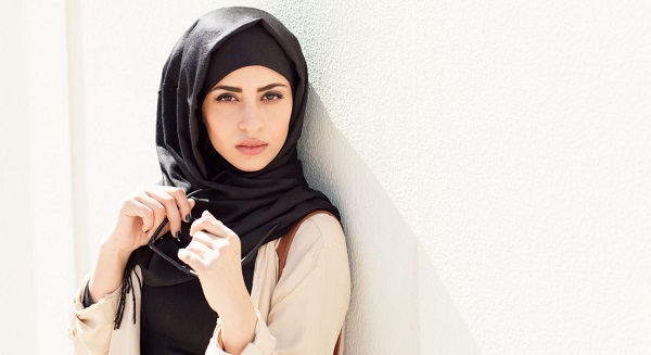 Serious Jordanian woman holding her sunglasses together posing