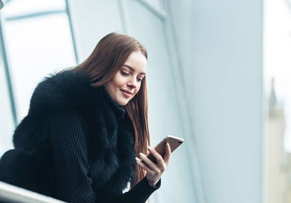 Smiling Slovakian girl standing with a phone in her hand