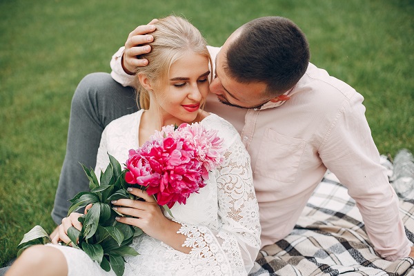 Smiling Albanian girl sitting with the flowers near her boyfriend