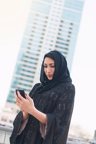 Adult Iraqi lady standing on the street with a phone in her hands